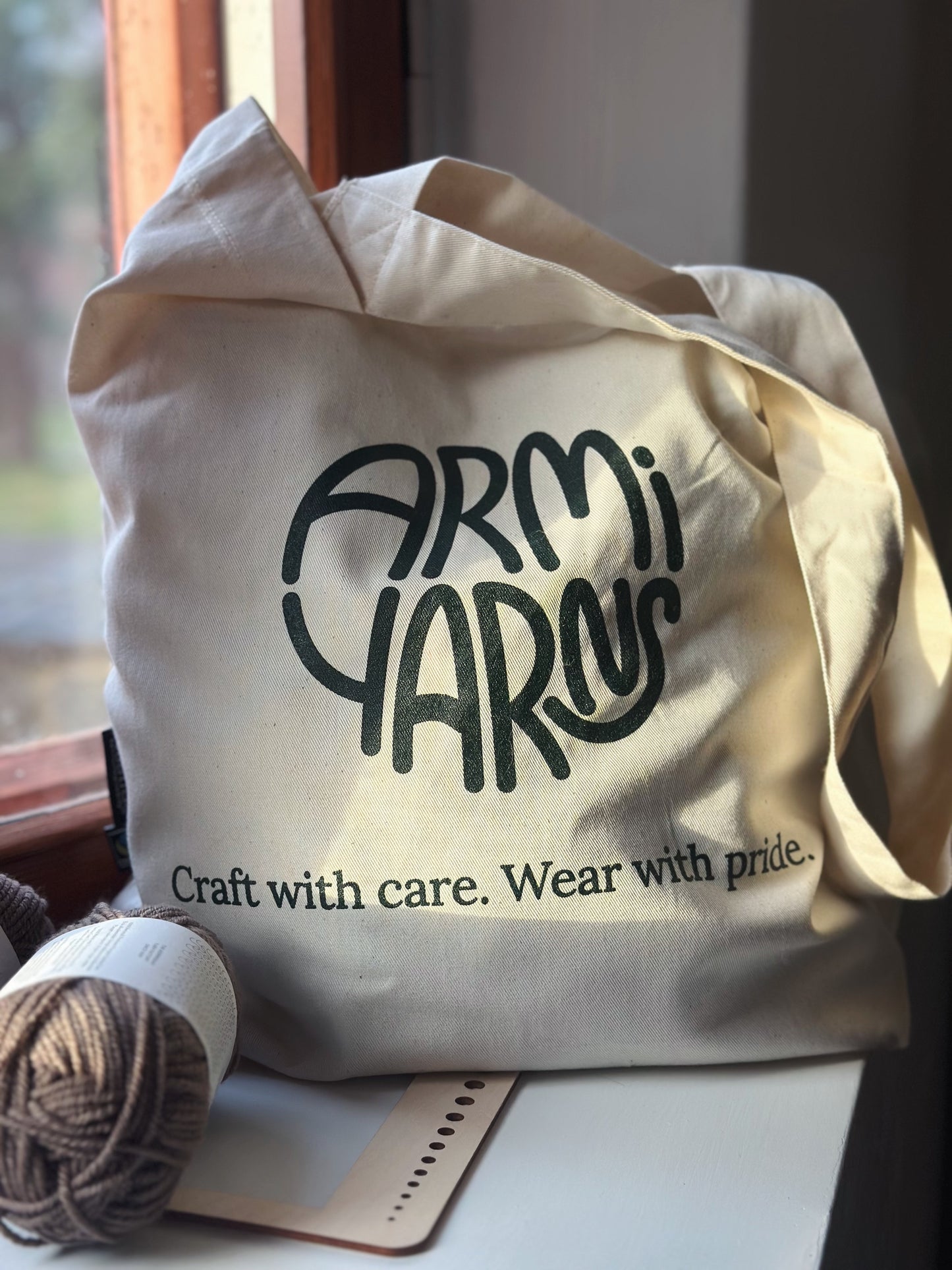 Kuvassa on Armi yarns -lankakaupan oma kangaskassi painetulla logolla.