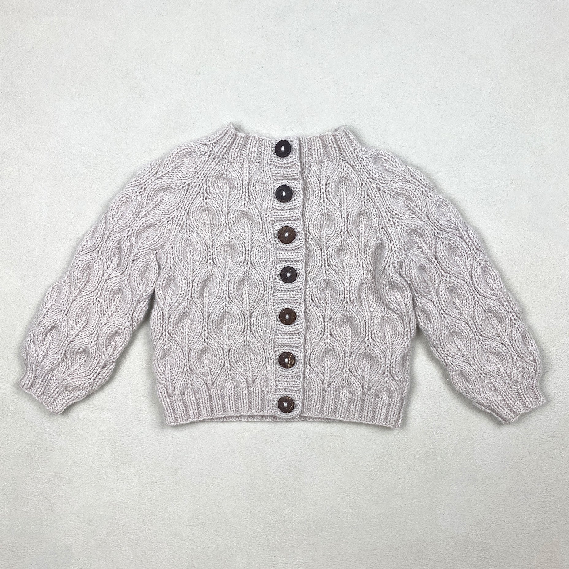 Kuvassa on Knitting for Olive (KFO) Olive Cardigan Baby -neuleohje (pattern).