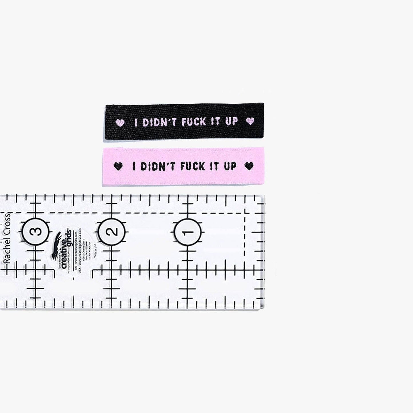 Kuvassa on Kylie & The Machine -kangasmerkit (labels) tekstillä I didn't fuck it up.