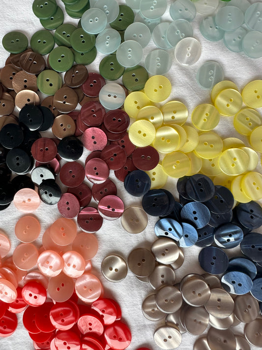 Kuvassa on eri värisiä nappeja vaatteisiin, joiden halkaisija on 18 mm.