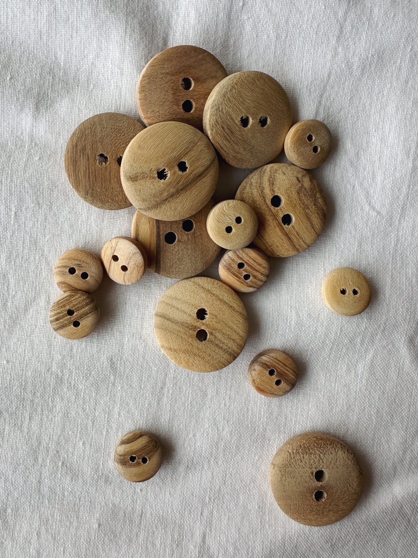 Kuvassa on eri kokoisia oliivipuisia nappeja (buttons). 