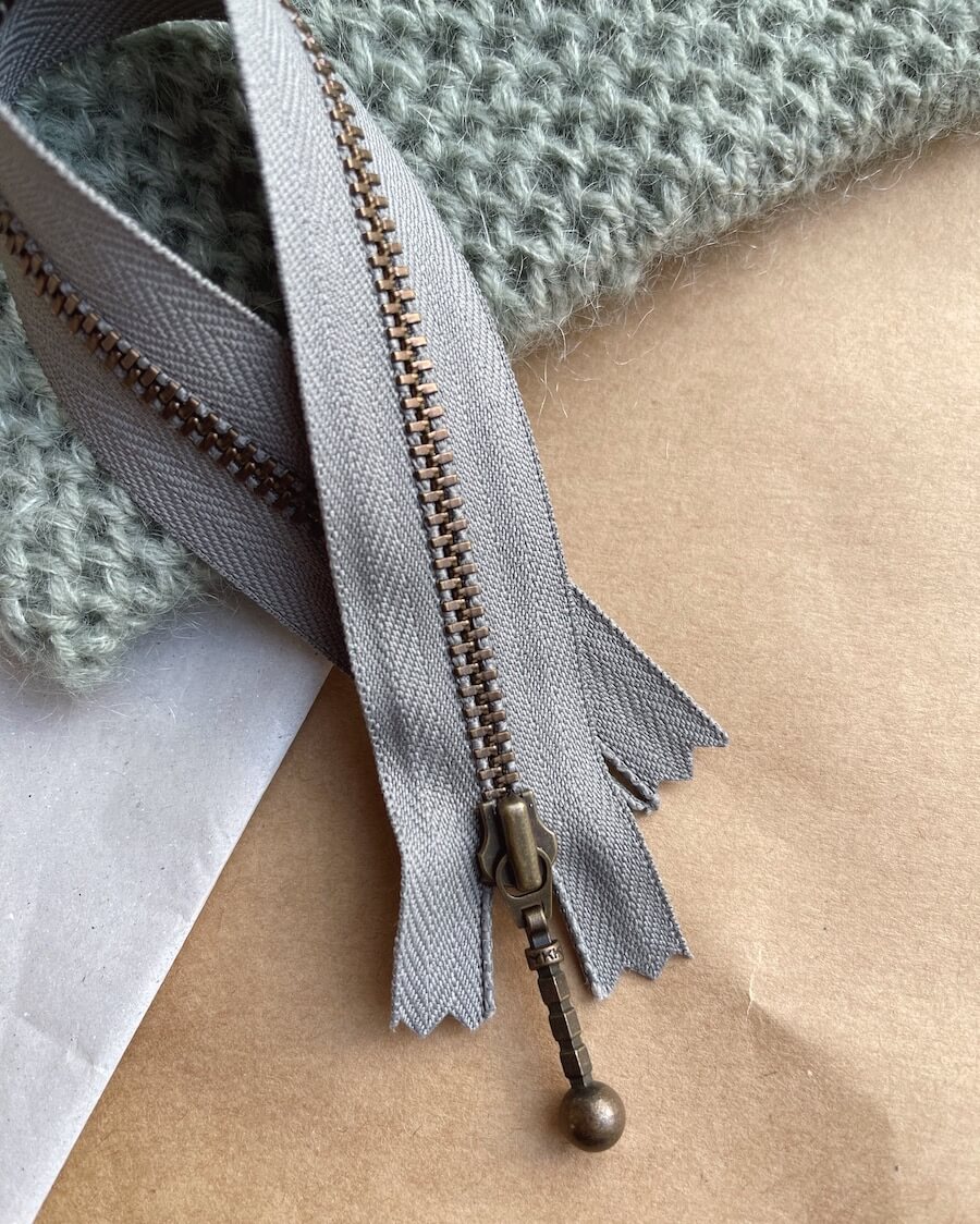 Kuvassa on PetiteKnit vetoketju (zipper) 23cm värissä Flint.