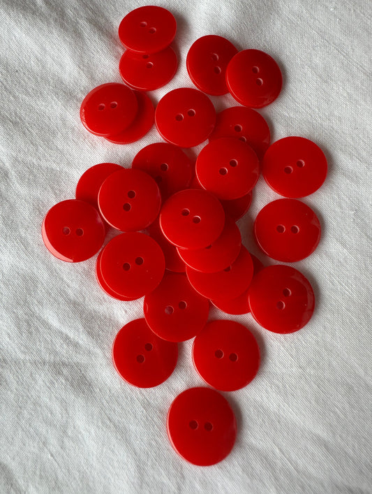 Kuvassa on punainen nappi vaatteeseen, minkä halkaisija on 18 millimetriä.