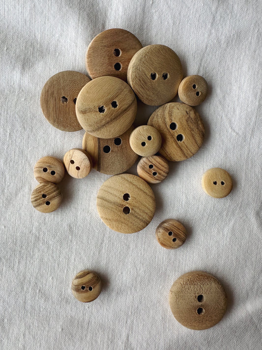 Kuvassa on eri kokoisia oliivipuisia nappeja. 